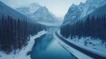 Snowy mountain river with road in wintry forest landscape aerial view photo