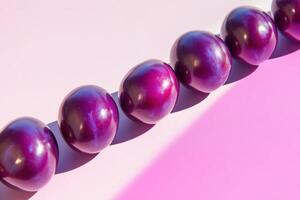 Row of shiny purple spheres on pink background with gradient light effects photo
