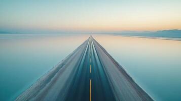Endless straight road through misty salt flats at sunrise with mountains in background photo