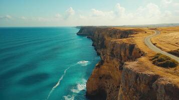 Coastal cliffscape with winding road and blue ocean under clear sky photo