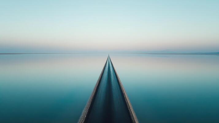 Tranquil highway reflecting on calm water at sunrise creating symmetry