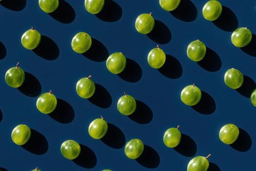 Pattern of fresh green grapes on dark surface with shadow effects highlighting fruit photo