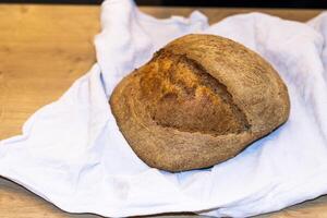 Shot of the freshly baked loaf of home made rye bread on the linen cloth. photo