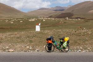 touring bicycle with panniers stands on the side of the road against the backdrop of mountains. travel bicycle. Kyrgyzstan photo