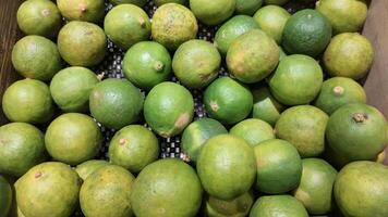 A crate of green limes sitting on top of a table photo