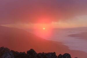The landscape view of the foggy mountain at sunrise or sunset nature background. photo