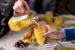 Happy Muslim family having iftar dinner during Ramadan dining table at home drinking a orange juice. photo