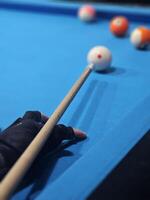 Billiard cue in hand of male player standing by pool table and concentrating before hitting white ball during game. photo