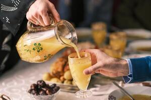 Happy Muslim family having iftar dinner during Ramadan dining table at home or restaurant wife and husband are drinking a healthy orange juice. photo