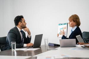 Two people in suits are sitting at a table with a presentation in front of them photo