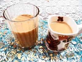 A cup of coffee and a cup of tea sit on a table photo