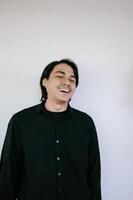 Smiling man in a black shirt laughing against a plain white background, photo