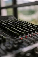 Close-up view of a sound mixer with numerous knobs and faders, ideal for music production photo