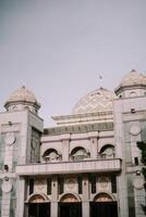 The serene domes of a mosque rise against a soft sky photo