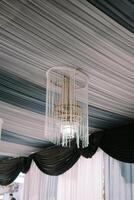 Ceiling draped with elegant fabric and decorative chandeliers looks nice photo