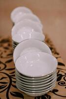 A neat stack of pristine white bowls awaits photo