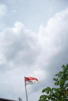 The Indonesian red and white flag waves proudly under a cloudy sky photo