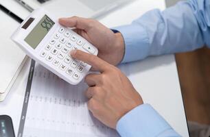 Businessman Saving money analyzing investment charts and pressing calculator buttons over documents. Accounting Concept photo