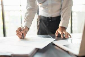 Close up of businessman hands signing or writing document paperwork and report Auditor analysis male professional hand making notes with Business Document. photo