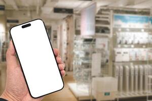 e for app or web site mockup. Smart phone with white screen in hand on Blur furniture store background.Mockup blank screen mobile phon photo