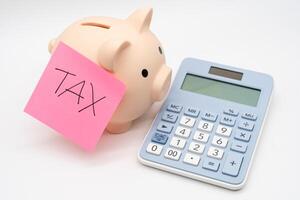 Tax Sticky note with piggy bank and calculator, Saving money for tax. Budget, tax, investment, financial, savings. Copy space. photo