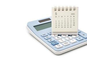 Simple desk calendar for MAY 2025 on calculator. Calendar concept with copy space. 2025 MAY calendar. calculator and forecast for finances in 2025. Money, Budget, tax, investment and financial. photo