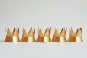 Six Golden Paper Crowns in a Row on a Minimalist White Background photo