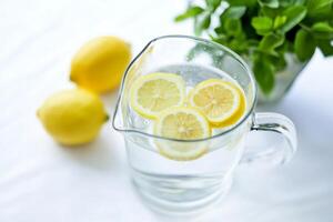 A pitcher of water with three lemons floating in it photo