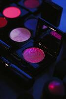 A collection of makeup products, including a pink glittery eye shadow photo