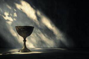 A small, ornate cup sits on a table in a dimly lit room photo