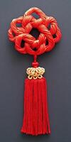 A red and gold tassel hangs from a red and gold ornament photo