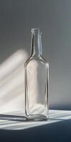 Minimalist Glass Bottle with Sunlit Shadows on a Neutral Background photo