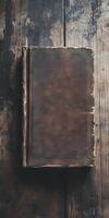 A book with a brown cover sits on a wooden table photo
