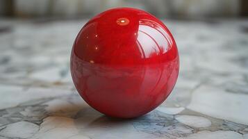 A close-up of a shiny, red sphere on a marble surface photo