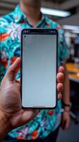 Hand holds smartphone against colorful Hawaiian shirt backdrop photo