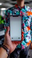 A man holds up a smartphone with a blank screen against a colorful patterned background photo
