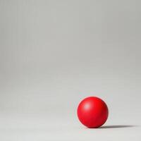 Red sphere rests on grey background photo