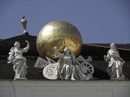 A statue of a globe on a building with statues of people photo
