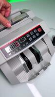 Hand puts some money into the cash counting machine. One hundred dollar bills appear from the device. Close up. Blurred backdrop. video