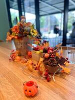 Festive autumn table arrangement with vibrant fall decorations and a miniature pumpkin. Warm tones and cozy ambiance evoke the spirit of the harvest season and Halloween celebrations photo