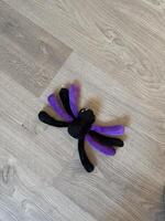 Plush spider toy with purple and black legs rests on a light wooden floor, creating a whimsical and playful atmosphere. Fun and creativity in everyday life photo