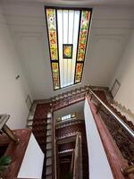 Spiral staircase with a vibrant stained-glass ceiling showcasing intricate patterns and colorful motifs. the artistic design and elegant decor a sense of timeless beauty and architectural mastery in photo