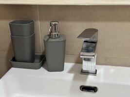 Sleek modern bathroom sink with a chrome faucet and neatly placed accessories. Clean and minimalist setting highlights functionality and elegance in home interiors photo