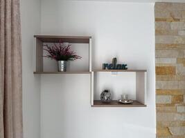 Minimalist wall shelf with a decorative flower pot and a teal relax sign. The background features a neutral wall with subtle textures and a soft curtain. Cozy and calming ambiance photo
