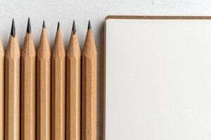 Close up of sharpened pencils next to a blank notebook photo