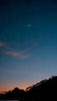 Crescent Moon Over Silhouetted Hills at Twilight photo