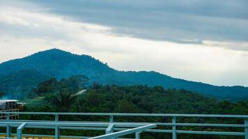 Scenic View of Forested Hills Under Cloudy Sky with a Modern Railing Foreground photo