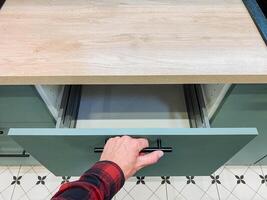 An individual is opening a kitchen drawer, likely engaged in a quest to find essential cooking utensils or necessary ingredients that are required for effective meal preparation photo