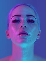 Close-up portrait of a womans face illuminated by pink and blue neon lights photo
