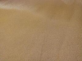 Fine golden sand covering a beach during a sunny day skies, creating a serene and tranquil atmosphere for relaxation photo